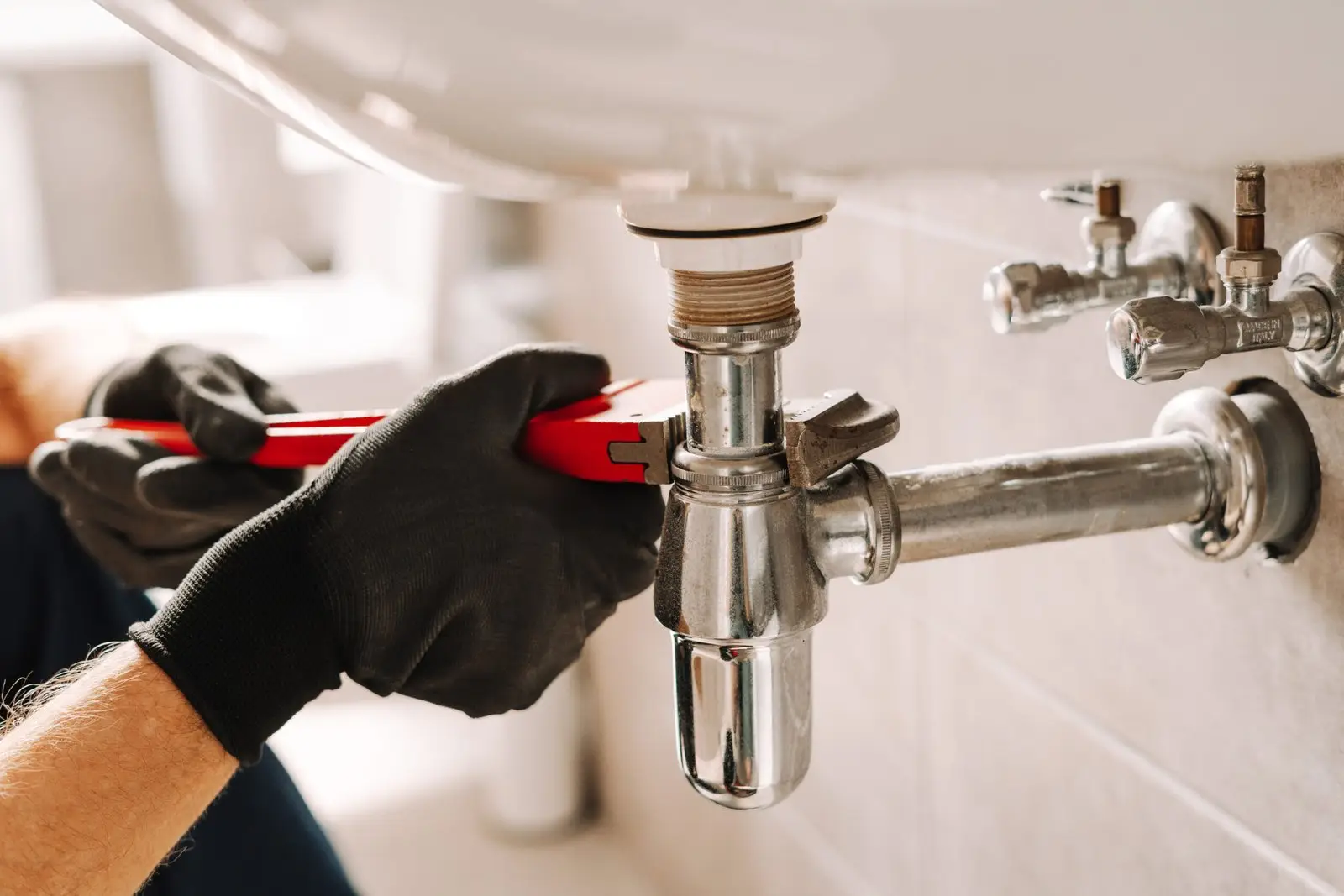 plumber-using-adjustable-wrench-repairing-sink-pipe-scaled.jpg